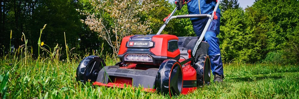 Person mäht Rasen mit Rasenmäher